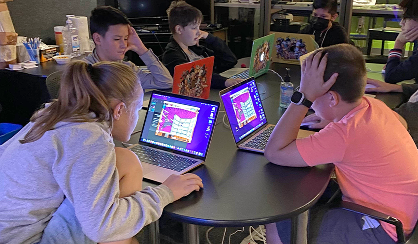 Students around a table using a laptop